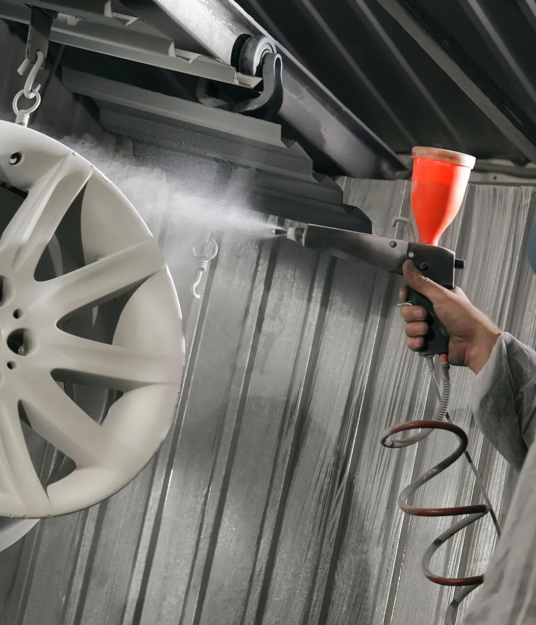 Alloy wheel being powder coated in a spray booth Alloy wheel being powder coated in a spray booth